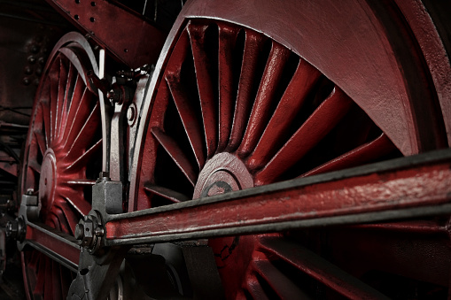 Nostalgic view of a bygone era. Close-up of the metal surfaces of the driving wheels and other complex mechanical components of a locomotive from the 1930s.