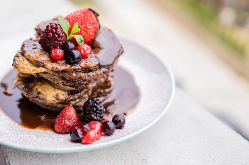 Delicious homemade pancakes with melted chocolate and red fruits on top.