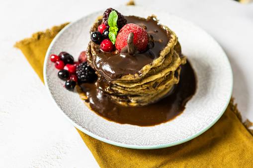Delicious homemade pancakes with melted chocolate and red fruits on top.