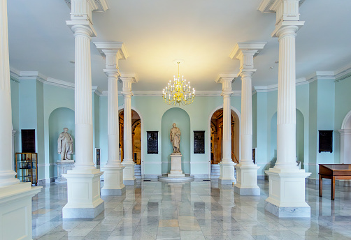 Boston, Massachusetts, USA - February 1, 2024: Doric Hall inside the Massachusetts State House. Its name comes from the Doric architectural style of its columns. The hall serves as reception hall for social gatherings and official ceremonies. A statue of George Washington is in the center.. To the left is a statue of Governor John A. Andrew.