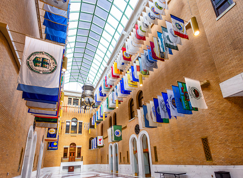 Boston, Massachusetts, USA - February 1, 2024: The Great Hall is an addition to the Massachusetts State House completed in 1990. There are flags from each of the 351 cities and towns of Massachusetts on display. The clock was designed by artist R. M. Fischer as a functional piece of artwork.