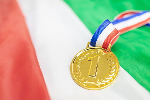 Radiant gold medal rests proudly on the Italian flag, symbolizing national pride and fervent support for Italian athletes in global sporting events