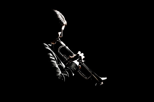 Trumpet player playing jazz musician. Woman playing trumpet brass instrument isolated on black