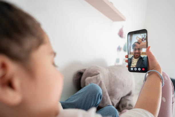 istock Unrecognizable girl holding a mobile phone, while having a video call with her father 1985168808