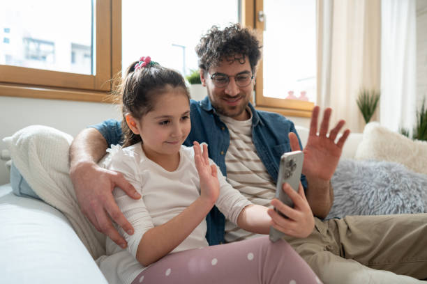 istock Caucasian father and daughter waving back during an video call 1985169358