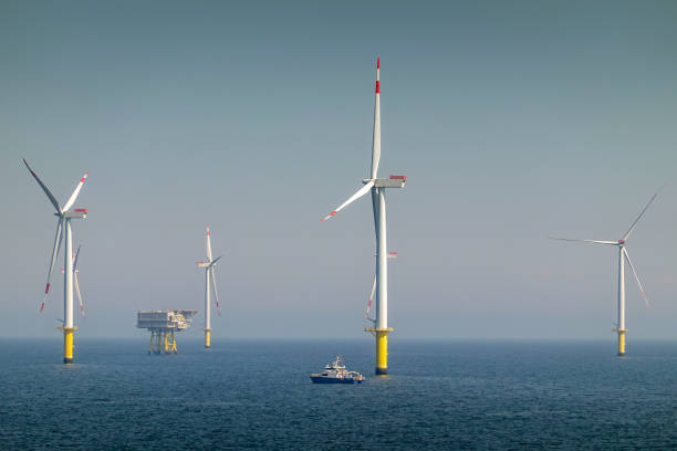 Epic Sunrise over Offshore Wind farm and substation on the horizont, vessel between them, bright sky, Borkum Riffgrund Germany Offshore Wind farm, wind turbines with substation on the horizont in sunset, wavy sea and moody, dramatic sky. Germany, Borkum Riffgrund offshore wind farm stock pictures, royalty-free photos & images
