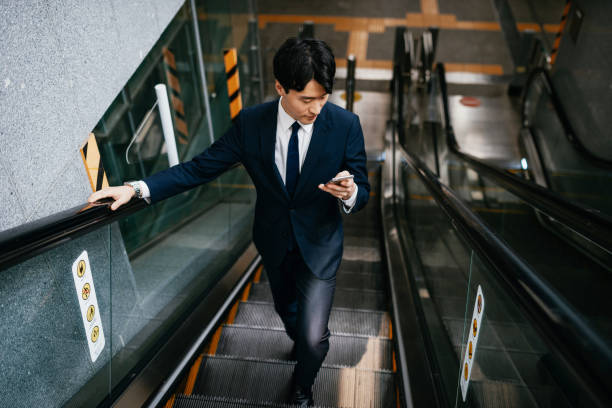 istock Korean businessman in full suit using escalator 1985173064