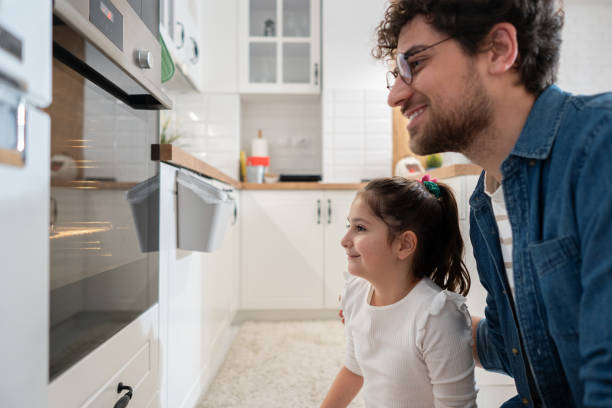 istock Caucasian father and daughter looking at the oven, while baking muffins 1985188326