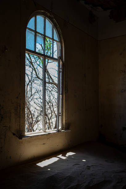 istock Abandoned interior space with an illuminated window in an old desert town 1985188332