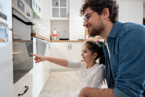 istock Caucasian father and daughter looking at the oven, while baking muffins 1985188333