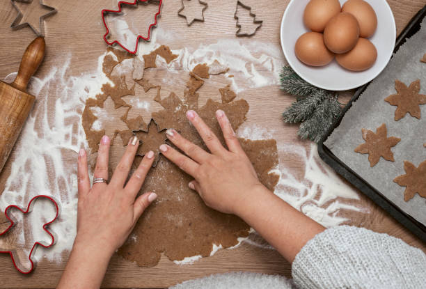 istock Woman cutting dough with christmas cookie cutters on table 1985195652