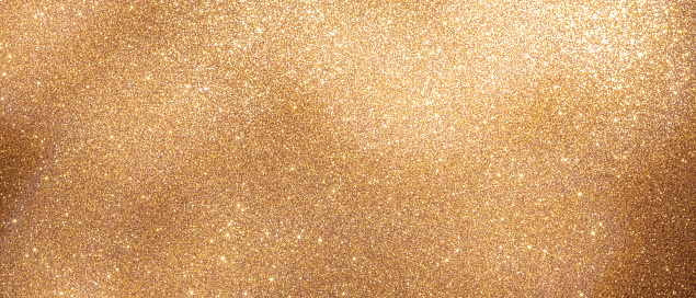 Image showcases a close-up of a sparkling gold glitter texture that glistens under bright illumination, providing a luxurious and festive vibe.