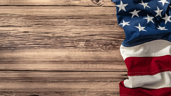A close-up image of the Stars and Stripes of an American flag displayed elegantly on a textured wooden plank background.