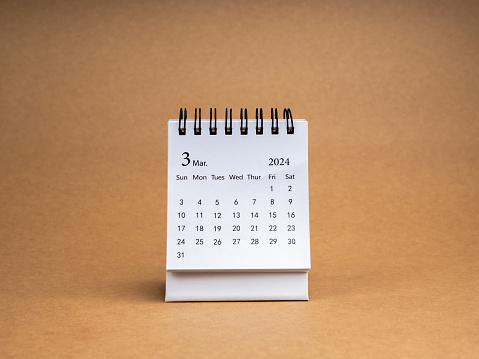A March 2024 desk calendar for the organizer to plan and reminder isolated on brown craft paper background, minimal style. White small table calendar with the page of third month.