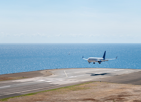 White aiplane landing in Madeira airport, runaway above Atlantic ocean