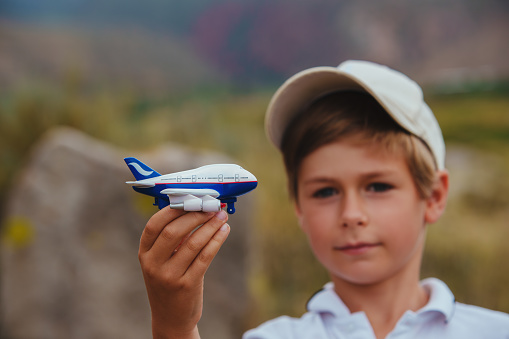 Boy in cap holding toy airplane, air travel concept, focus on airplane