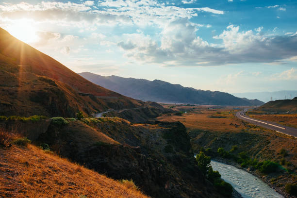 istock Picturesque mountain landscape with river and highway at sunset light 1985245849