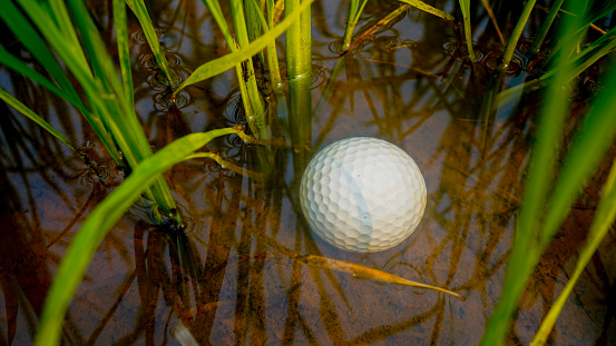 golf ball in water hazard. Problems and obstacles of Golf balls are in danger from water. Problems and obstacles of golfers. White golf ball falls into the water One of the obstacles to playing golf