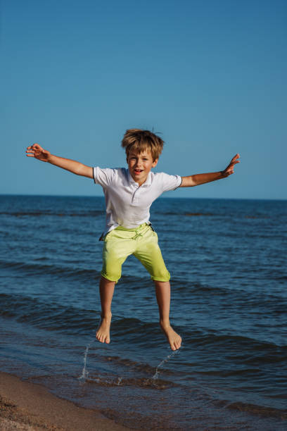 istock Happy boy jumping on the beach at summer day 1985246059