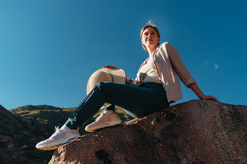 Young woman hiker sitting on top of the mountain