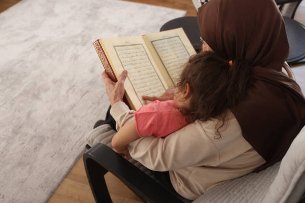 Grandmother teaches her granddaughter to read the Quran stock photo