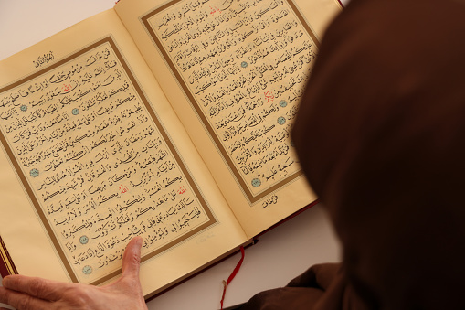 Senior muslim woman reading Quran at home