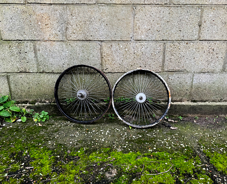 Two bike wheels left in an alley
