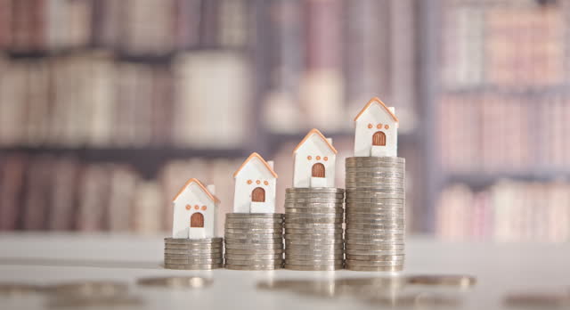 Mortgage loan or home equity loan, financial concept : Tiny model residential house perched atop coin stacks, depicting home loan or borrowing money to purchase a new home for first time homebuyer.