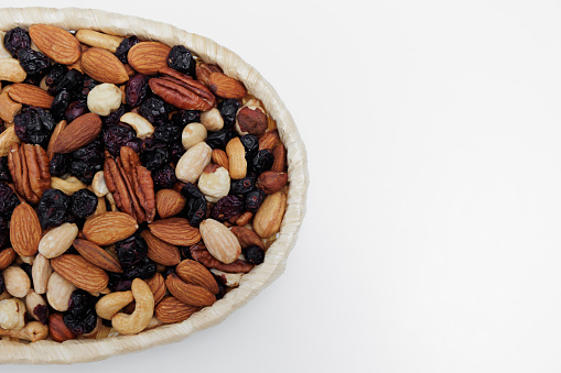 mix of various nuts in wooden bowl and copy space over white table background
