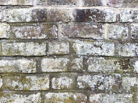 A rustic mixed colour brick wall with scruffy mortar
