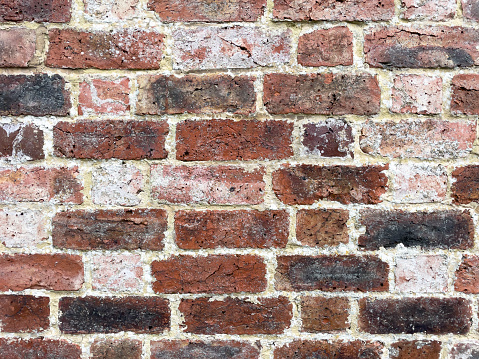 A rustic mixed colour brick wall with scruffy mortar