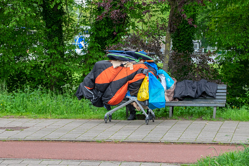 Homeless Man Sitting On A Bench With Shopping Cart At Amsterdam The Netherlands 10-5-2023