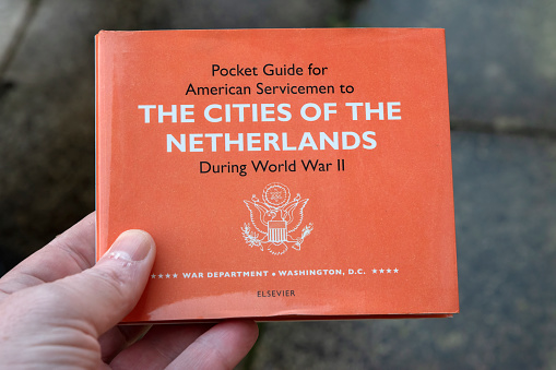 Holding A Pocket Guide For American Servicemen Of The Cities Of The Netherlands During World War II At Amsterdam The Netherlands 26-1-2023