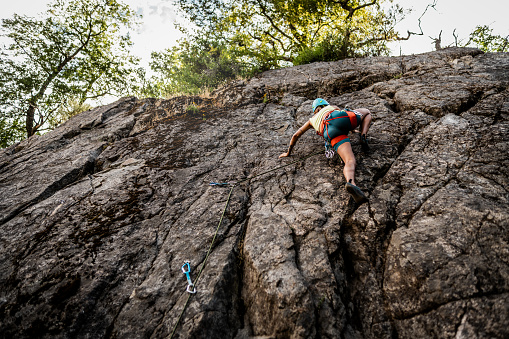 Young climber climbing cliff