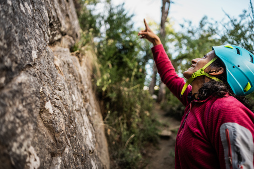 Female climber pointing upwards while climbing a hill