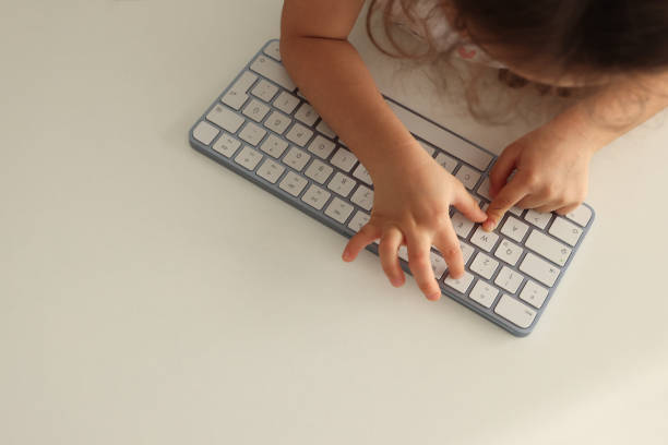 istock Little girl uses computer keyboard 1985487490