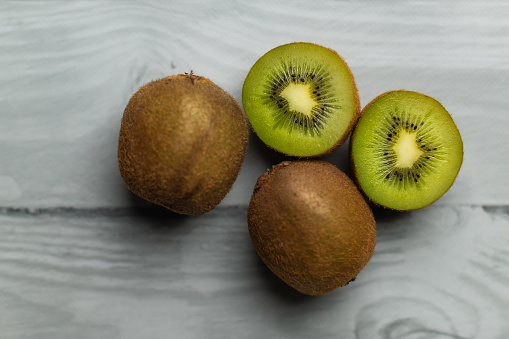 Whole and cut kiwi on a wooden white table. Green fruits. Vitamin C. Fruits in the kitchen.