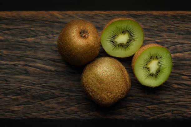 istock Whole and cut kiwi on a wooden brown table. 1985488006