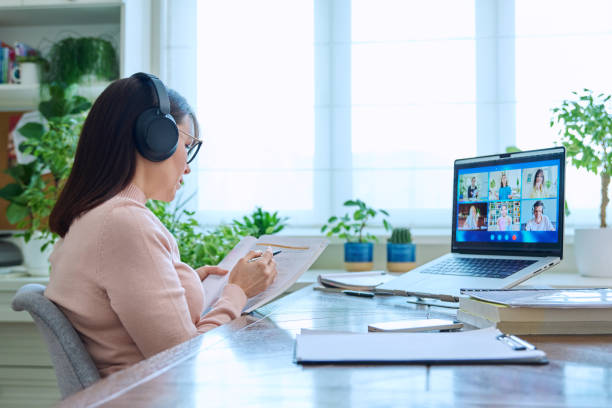 istock Woman teacher in headphones teaching online, high school students on computer screen 1985488530