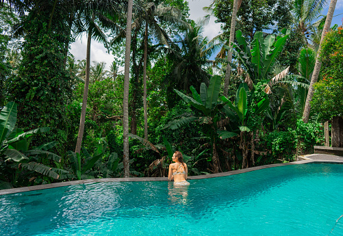 Woman swimming in the pool with view on  lush green jungles in Ubud, Bali
