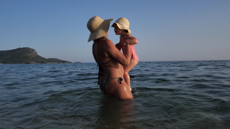 Summer on beautiful sandy beach. Mother and toddler girl enjoying summer time