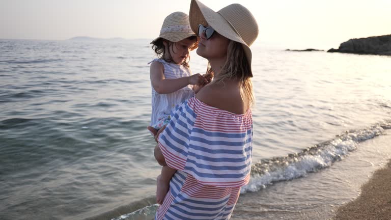 Summer on beautiful sandy beach. Mother and toddler girl enjoying summer time