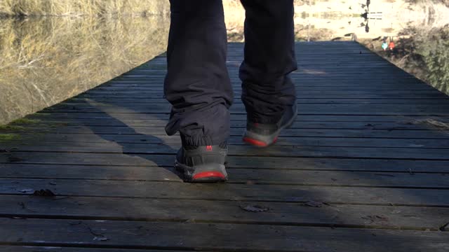 Man walks on a wooden platform overlooking a reservoir