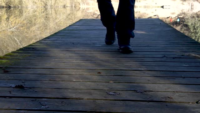 Man walks on a wooden platform overlooking a reservoir
