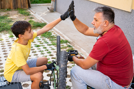 Father and son repairing a bicycle in backyard