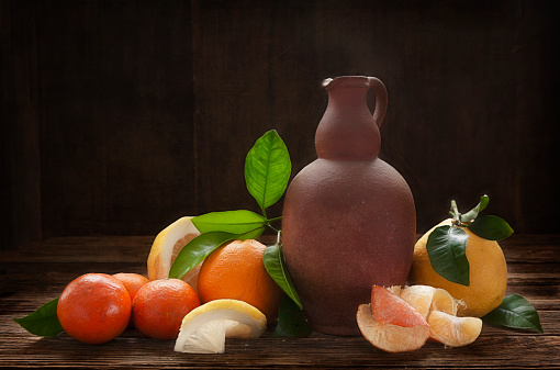 Oranges, tangerines, lemons and vintage ceramic jug on an old wooden table. Artistic Still Life in Vintage Style.