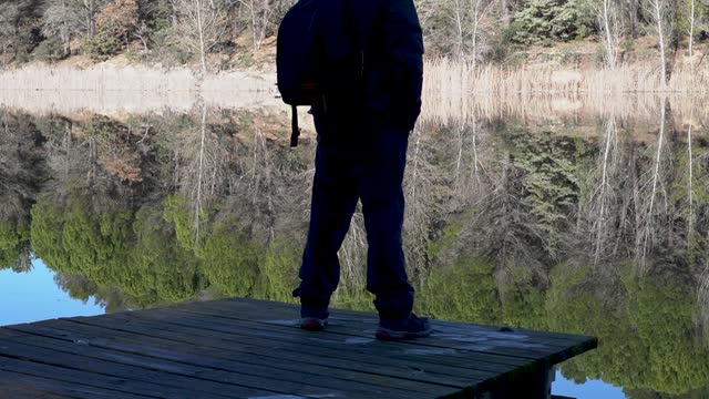 Man standing on edge of small fishing pier looking into reservoir