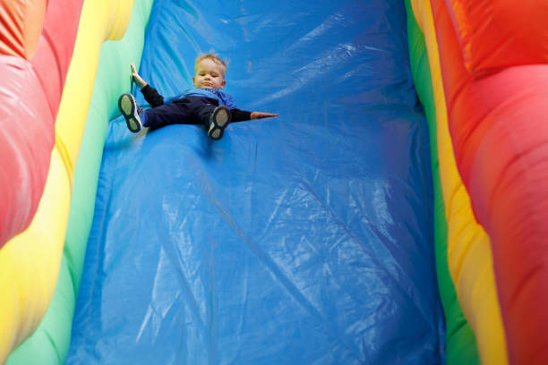 istock A little scared child sliding down an a blue inflatable slide. There is free space for text in the image 1985588540