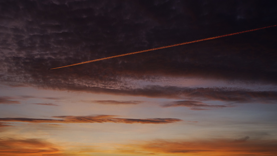 Passenger jet leaves a contrail across a dramatic dawn sky.