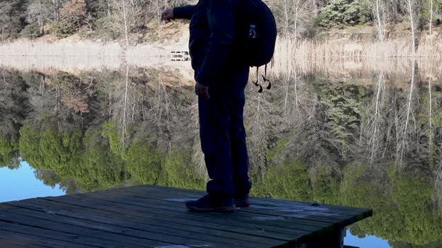 Man standing on edge of small fishing pier looking into reservoir